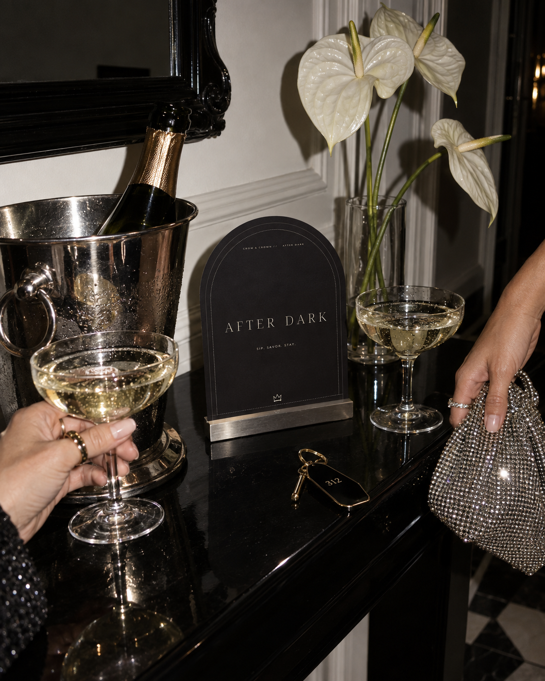 The After Dark Party arched printable sign beside champagne bottles, coupe glasses and white flowers