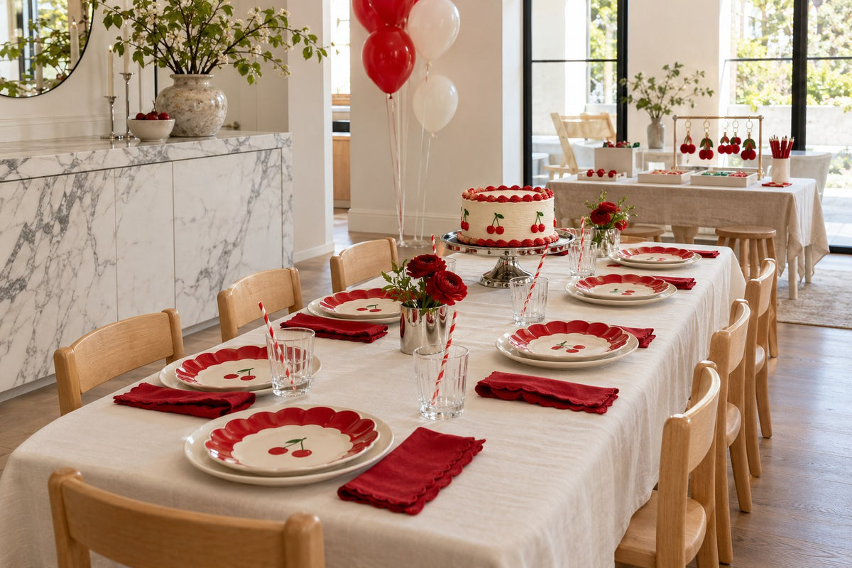 Red and ivory kids’ cherry birthday table with cake, cherry plates and a separate charm-making station.