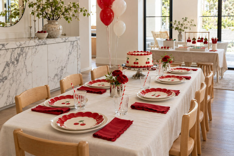Red and ivory kids’ cherry birthday table with cake, cherry plates and a separate charm-making station.