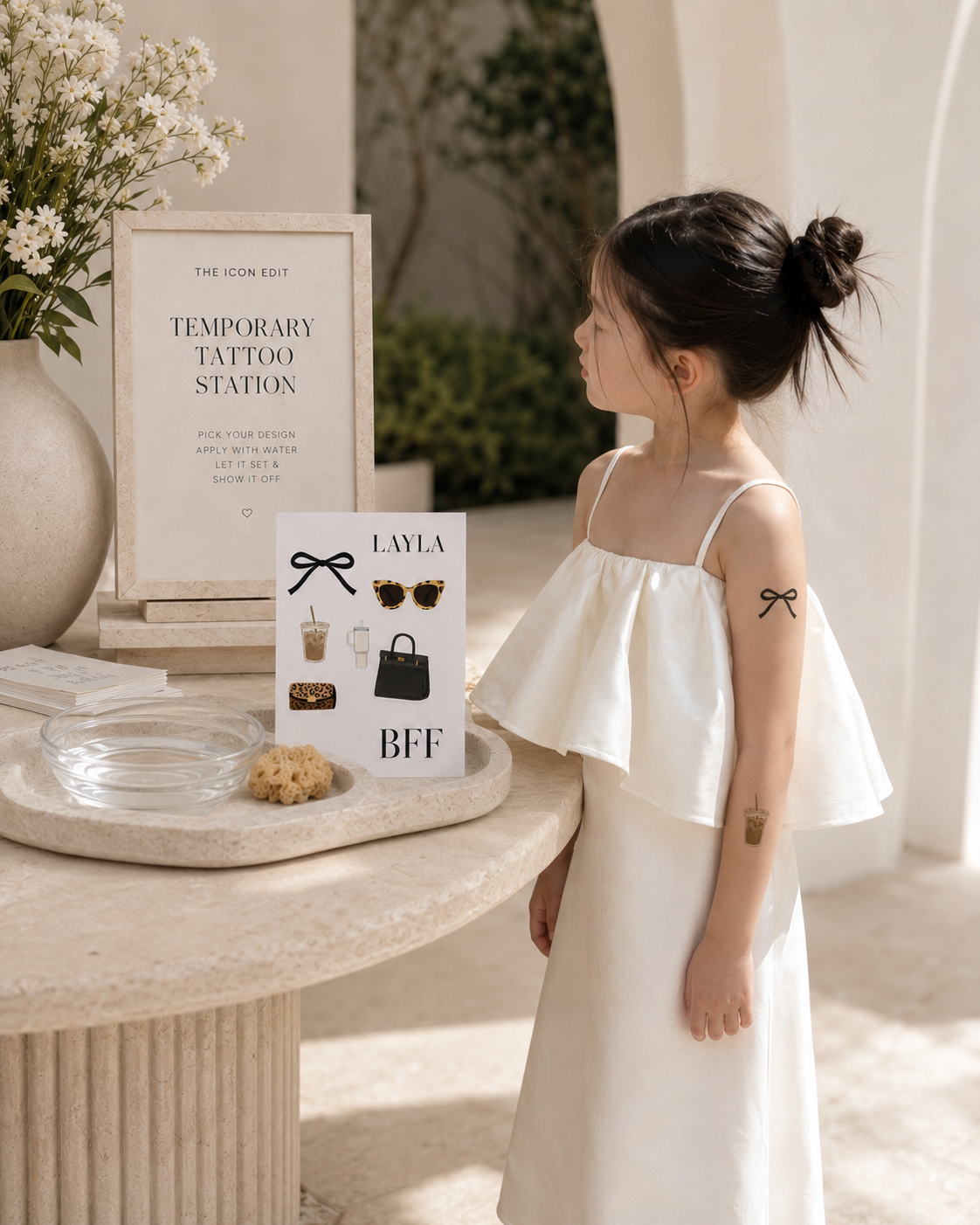 Girl showing a bow temporary tattoo beside The Icon Edit tattoo station
