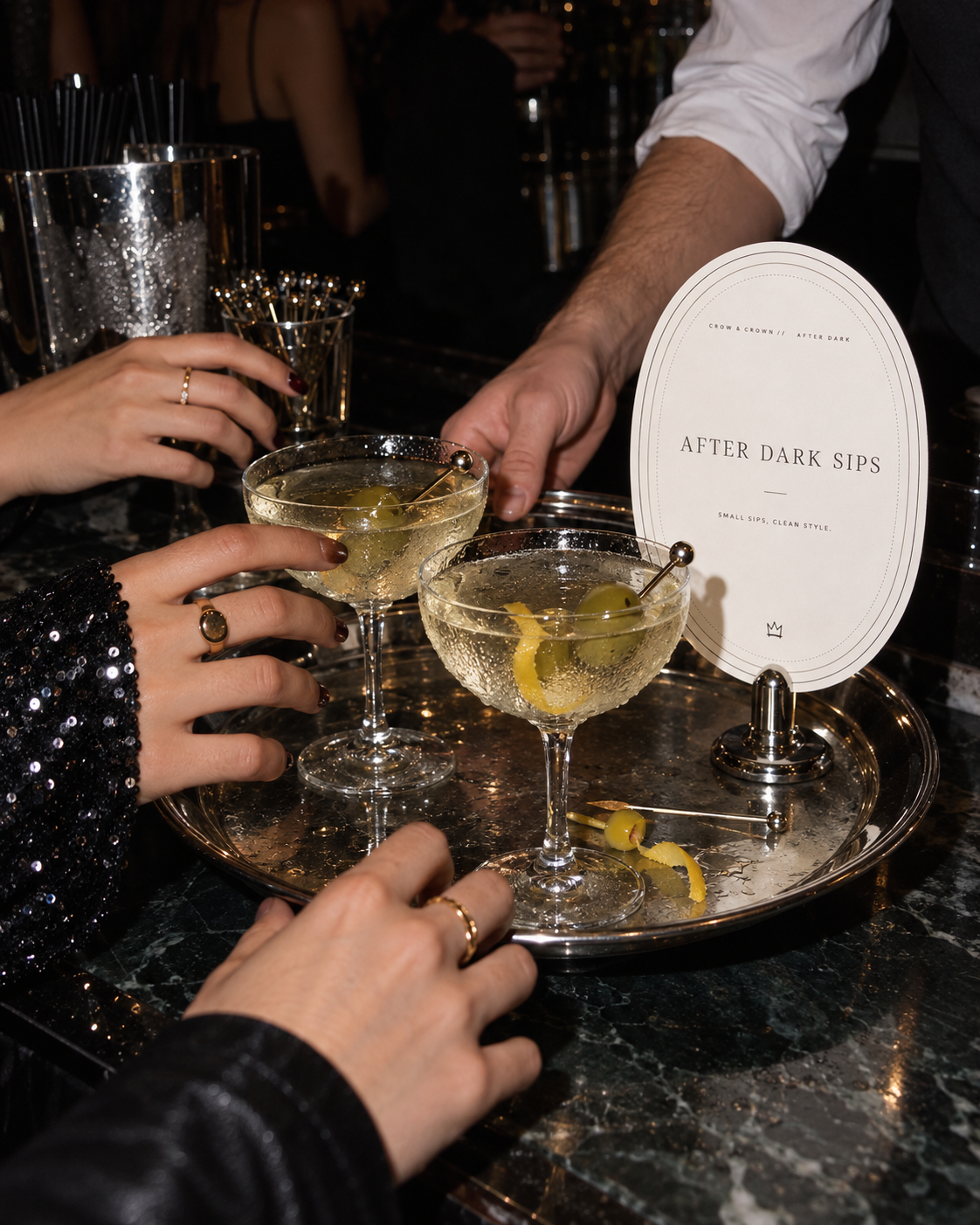 After Dark Sips printable sign behind a silver tray of cocktails held by party guests