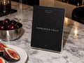 Forbidden Fruit cocktail-party printable beside cherries and sliced figs on marble