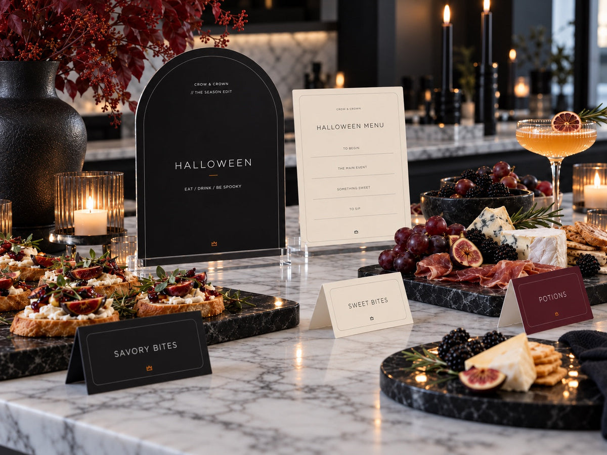 Halloween Edit welcome sign, ivory menu and food tent cards beside a buffet on marble