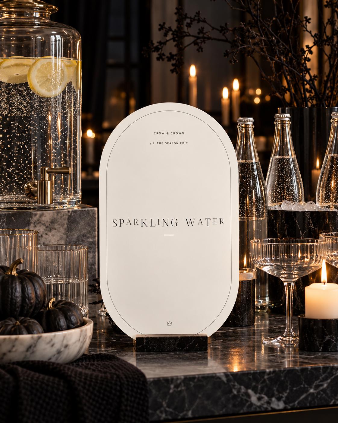 Sparkling Water Halloween printable beside glass bottles and black pumpkins