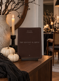 The Haunt Is Open Halloween printable on a console beneath a round mirror