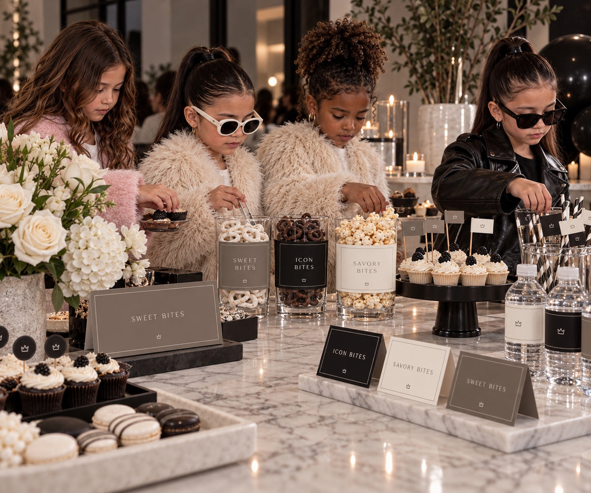 Minimal Fashion birthday snack station with cup wraps, food labels and guests at a marble counter